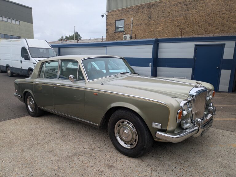Two-tone classic Bentley saloon with chrome grille and bumpers outside a specialist vehicle restoration workshop.