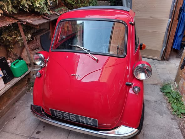 Red vintage BMW Isetta bubble car with chrome headlights and original front-opening door.